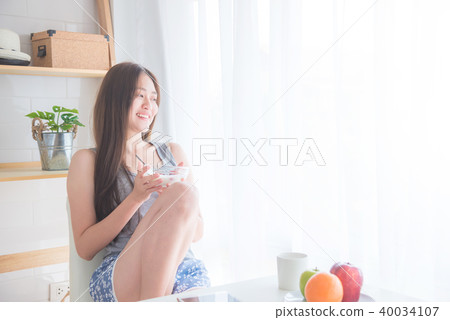 woman sitting near by window and holding yogert woman sitting near by window and holding yogert 40034107