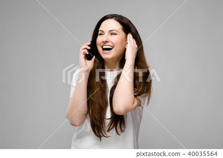 Emotional smiling happy plus size model standing in studio looking in camera talking on phone with Emotional smiling happy plus size model standing in studio looking in camera talking on phone with 40035564