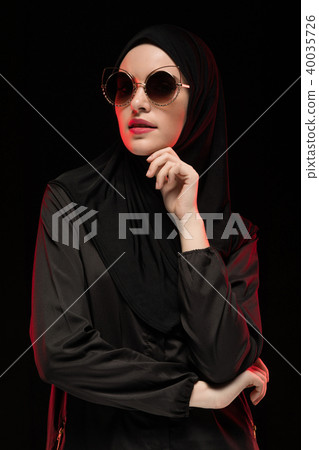 Portrait of beautiful stylish young muslim woman wearing black hijab and sunglasses as modern Portrait of beautiful stylish young muslim woman wearing black hijab and sunglasses as modern 40035726
