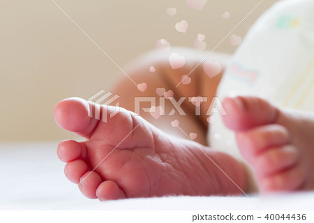Newborn baby infant feet on white bed with hearts Newborn baby infant feet on white bed with hearts 40044436