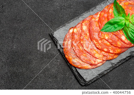 Salami or chorizo sausage slices on stone serving board 40044756
