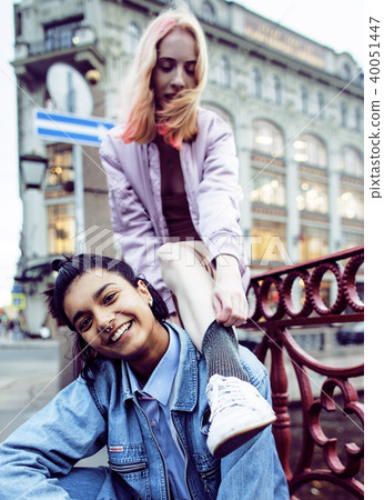 Two teenage girls infront of university building smiling, having 40051447