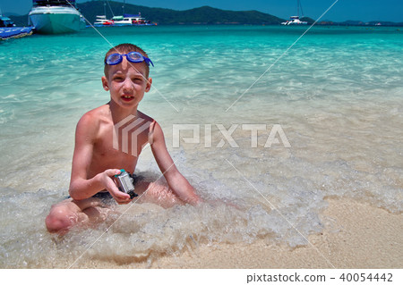 Boy with swimming goggles sits in turquoise water 40054442