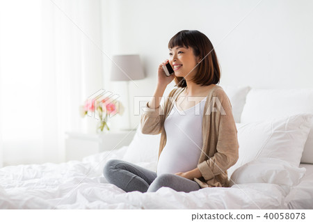 happy pregnant woman calling on smartphone at home happy pregnant woman calling on smartphone at home 40058078