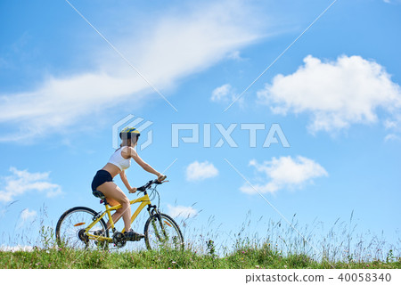 Young happy woman cycling on mountain bike at summer day 40058340