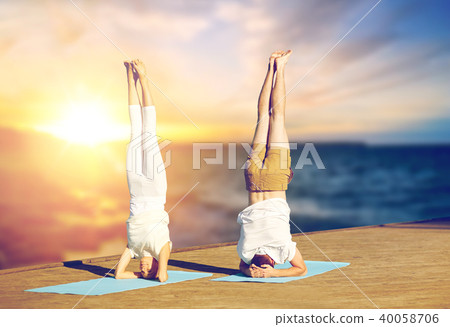 couple doing yoga headstand on mat outdoors 40058706