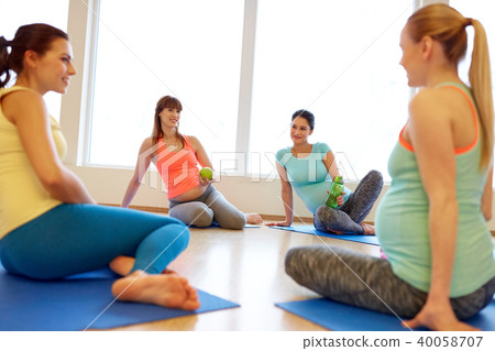 happy pregnant women sitting on mats in gym happy pregnant women sitting on mats in gym 40058707