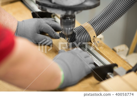 carpenter with drill press and board at workshop carpenter with drill press and board at workshop 40058774