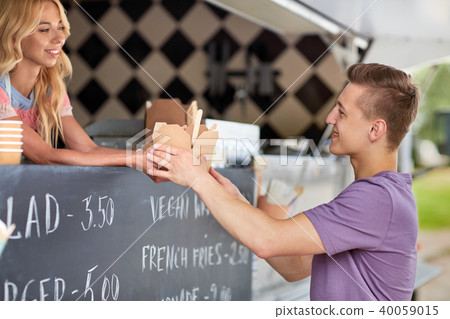 saleswoman at food truck serving male customer 40059015