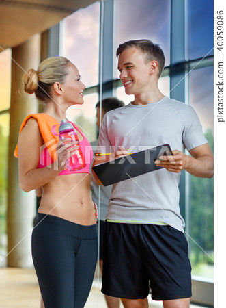 smiling young woman with personal trainer in gym 40059086