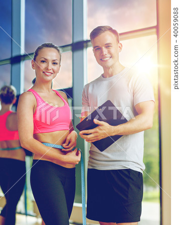 smiling young woman with personal trainer in gym 40059088
