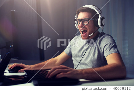 man in headset playing computer video game at home man in headset playing computer video game at home 40059112