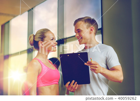 smiling young woman with personal trainer in gym 40059262