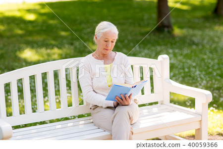 senior woman reading book at summer park 40059366