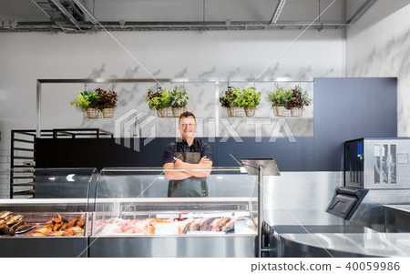 male seller with seafood at fish shop fridge 40059986