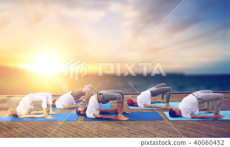 group of people doing yoga bridge pose outdoors 40060452