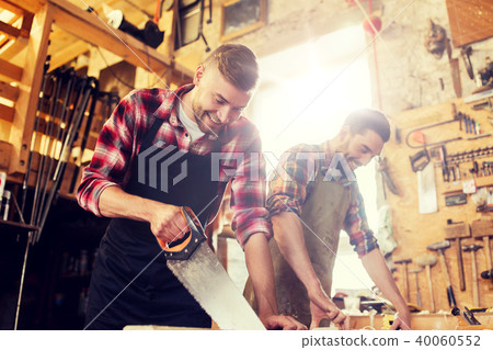 carpenters working with saw and wood at workshop 40060552
