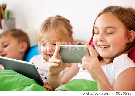 happy kids with tablet pc and and smartphone in bed happy kids with tablet pc and and smartphone in bed 40060583