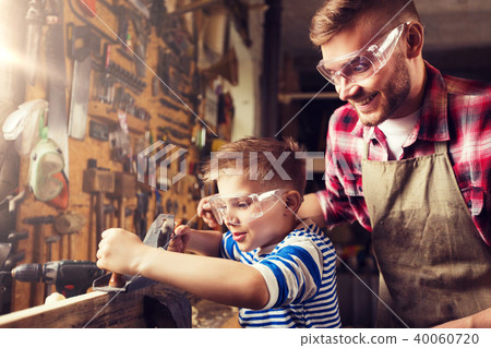 father and son with plane shaving wood at workshop 40060720