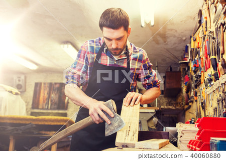 carpenter with ax and board working at workshop 40060880