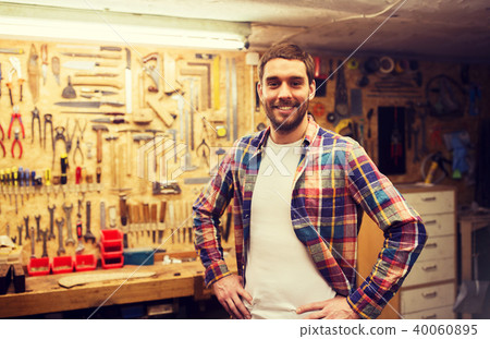 happy young workman in checkered shirt at workshop happy young workman in checkered shirt at workshop 40060895