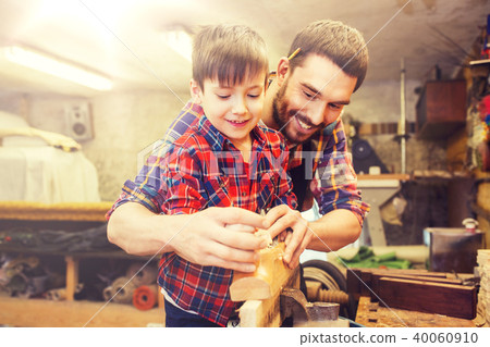 father and son with plane shaving wood at workshop father and son with plane shaving wood at workshop 40060910