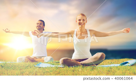 happy couple making yoga and meditating outdoors 40061064