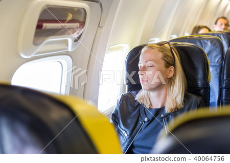 Tired blonde casual caucasian lady napping on seat while traveling by airplane. Tired blonde casual caucasian lady napping on seat while traveling by airplane. 40064756