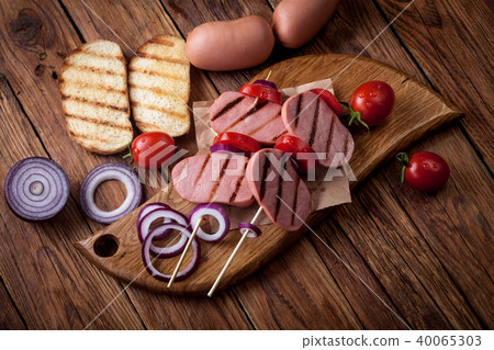 skewers of grilled sausages with tomatoes onions, croutons on the old wooden table 40065303