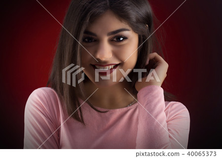 Brunette girl with long and shiny wavy hair . Beautiful model on red background. 40065373