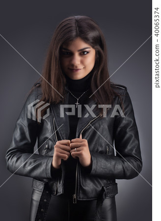Brunette girl in a black leather jacket . Beautiful model on a gray background. Brunette girl in a black leather jacket . Beautiful model on a gray background. 40065374