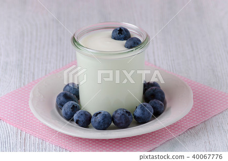 a cup of yogurt with blueberrys on the table 40067776
