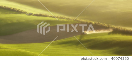 tractor plows the field in the spring 40074360