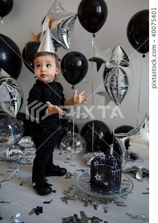 boy stands next to a festive black cake 40075401