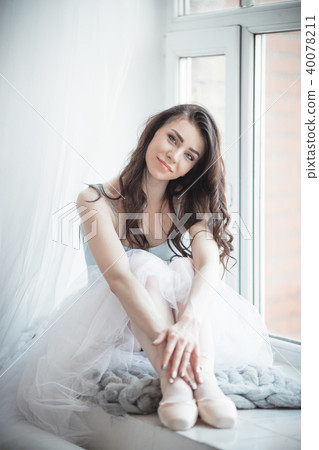 Beautiful ballerina girl is sitting on windowsill in studio Beautiful ballerina girl is sitting on windowsill in studio 40078211