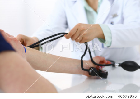 Doctor checking blood pressure of the patient, closeup. Cardiology in medicine and health car Doctor checking blood pressure of the patient, closeup. Cardiology in medicine and health car 40078959