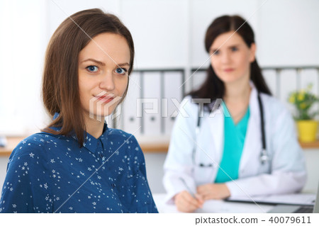 Doctor and patient having a talk while sitting at the desk. Focus on young beautiful woman looking Doctor and patient having a talk while sitting at the desk. Focus on young beautiful woman looking 40079611