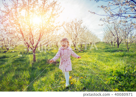 Little baby girl that runs between flowering trees at sunset. Ar Little baby girl that runs between flowering trees at sunset. Ar 40080971