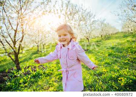 Little baby girl that runs between flowering trees at sunset. Ar Little baby girl that runs between flowering trees at sunset. Ar 40080972
