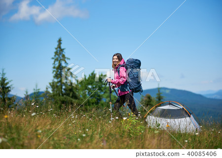 Woman hiker near camping in the mountains with backpack and trekking sticks in the morning 40085406