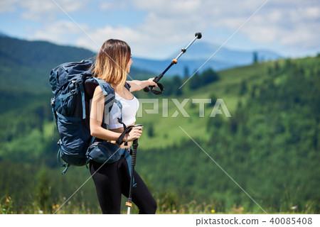 Sporty woman hiker with backpack and trekking sticks hiking in the mountains Sporty woman hiker with backpack and trekking sticks hiking in the mountains 40085408