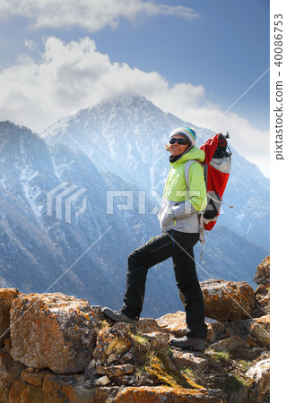A girl backpacker stands on top of a mountain 40086753