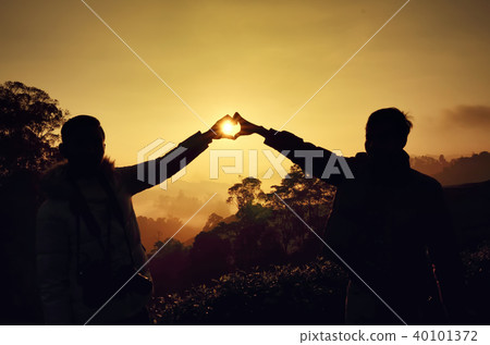 Silhouette of happy man holding hand over sunrise Silhouette of happy man holding hand over sunrise 40101372