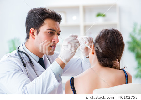 Doctor checking patients ear during medical examination 40102753