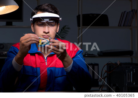 Computer specialist repairing PC late at night 40105365
