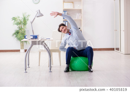 Employee exercising with swiss ball during lunch break Employee exercising with swiss ball during lunch break 40105819
