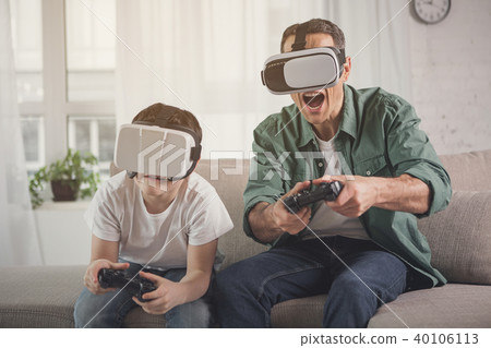 Excited man and boy entertaining with vr headsets Excited man and boy entertaining with vr headsets 40106113