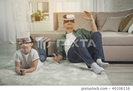 Shocked father and son watching video on virtual reality headsets Shocked father and son watching video on virtual reality headsets 40106116