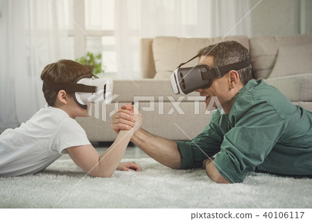 Carefree parent and kid competing in arm wrestling with gadgets 40106117