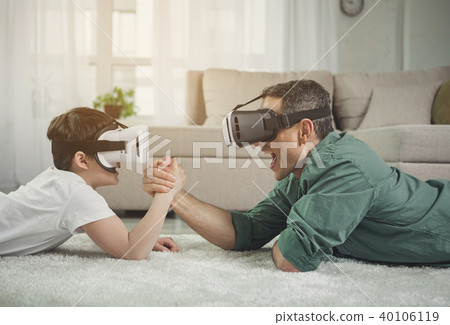 Excited father and son lying on floor and arm-wrestling 40106119
